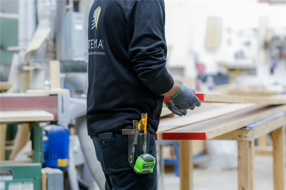Employé d'Intermat manipulant des composantes d'un escalier sur mesure dans l'atelier de fabrication, avant la finition et l'installation sur un chantier résidentiel ou commercial.